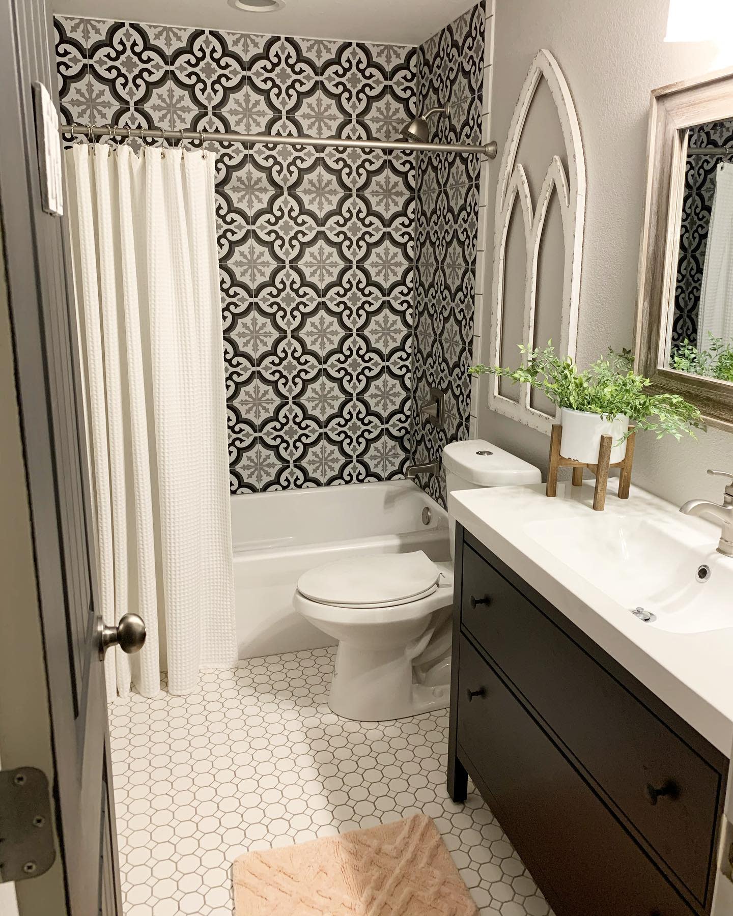 Elegant bathroom with black-and-white patterned wall tiles, hexagonal floor tiles, and modern vanity.